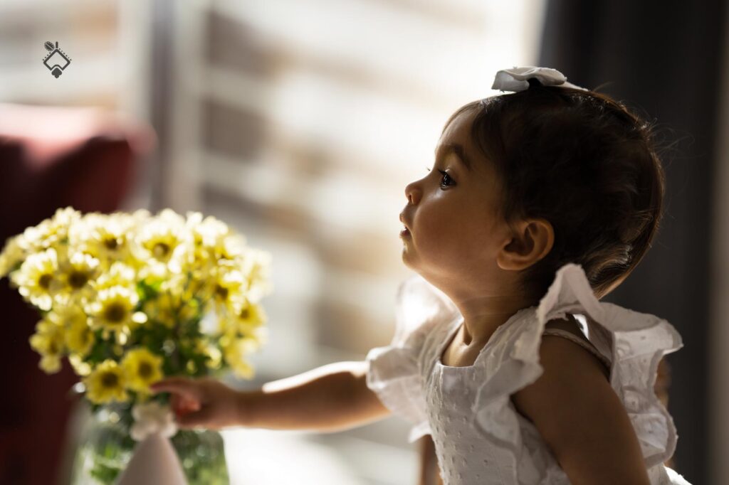 عکس چهره کودک با پس زمینه گل طبیعی و نور پنجره